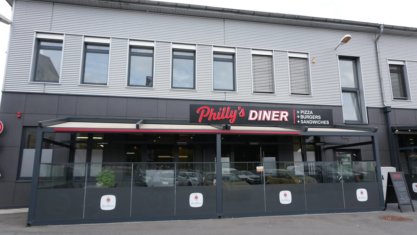 Außenansicht von Philly's Diner mit Terrasse und roter Leuchtschrift